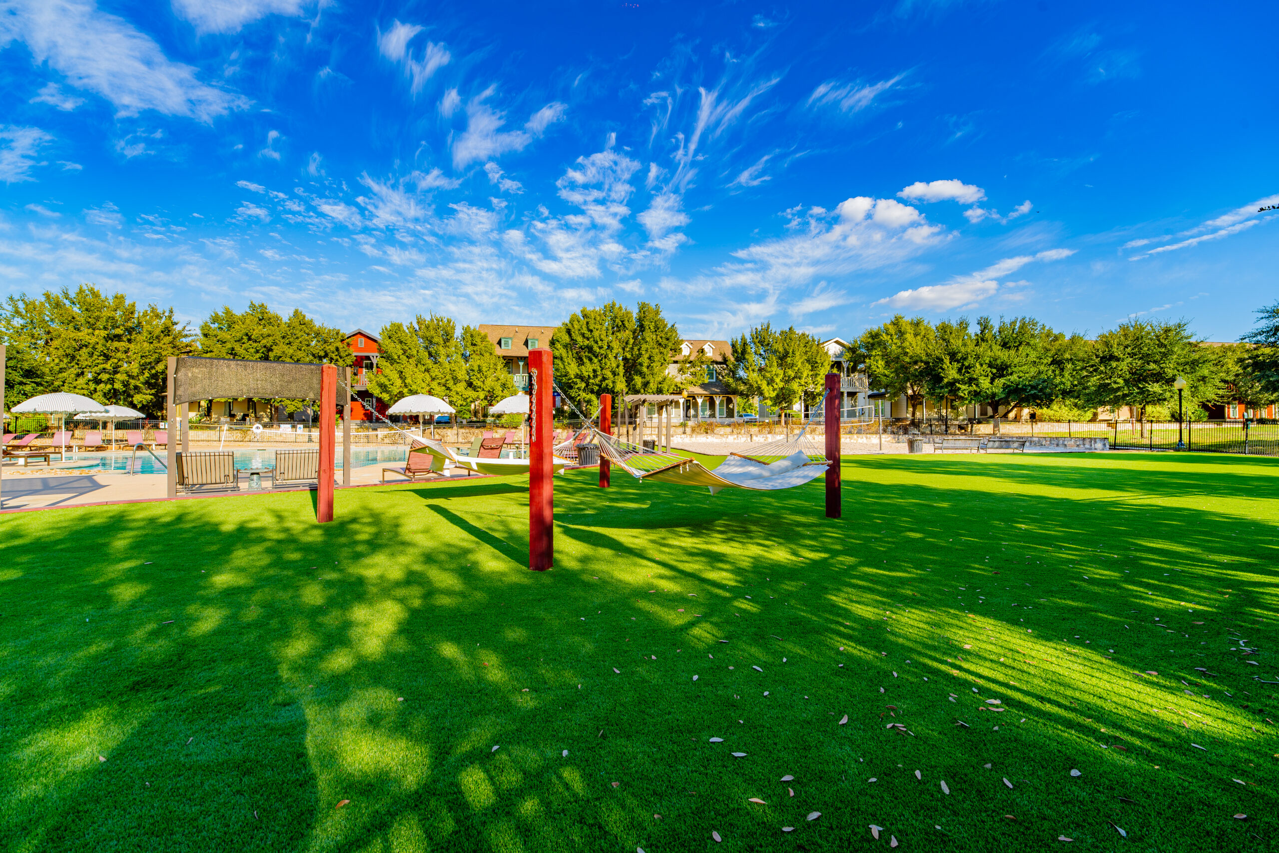 DSC03030 Sunny fenced dog park with artificial turf, shade trees, and red agility equipment