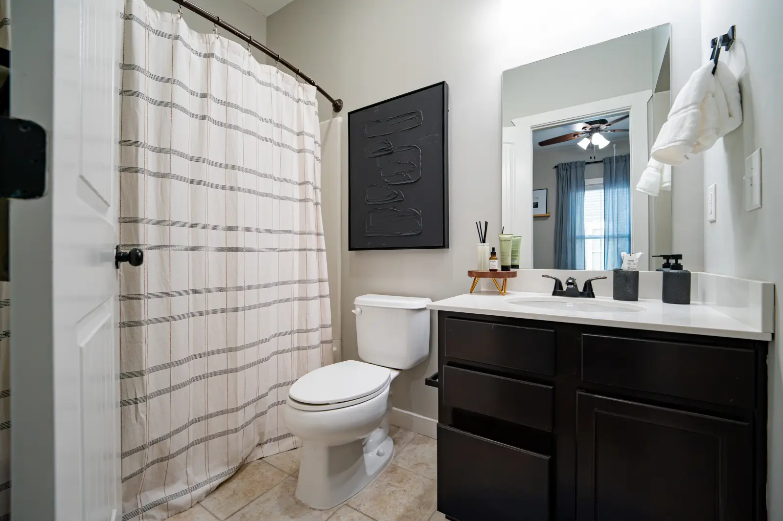DSC03132 Bathroom with a striped shower curtain, dark wood vanity, white countertop, and toilet